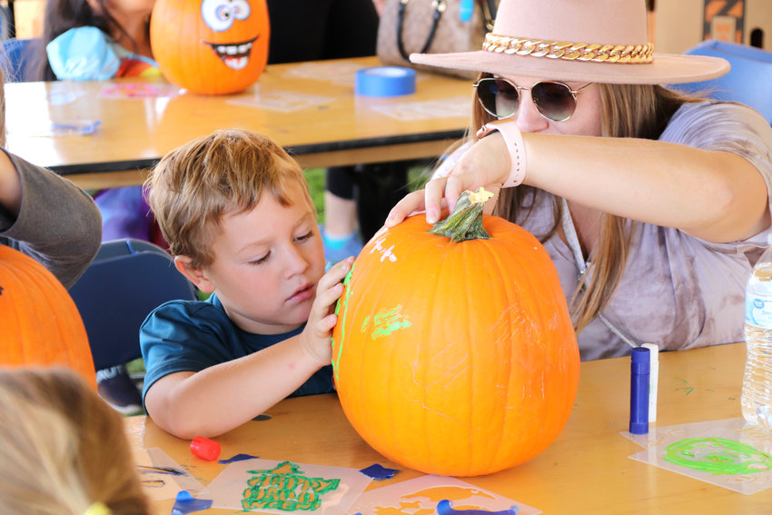 Wyatt Fulenwider, 4, of Thornton helps his mom, Ashley, decorate a pumpkin with paint at Thornton’s 2021 Harvest Fest Oct. 2 at the York Street Community Park. The festival featured fall-themed attractions like games and a farmer’s market as well as musical performances, Native American dancers and luchadores doing wrestling exhibitions.